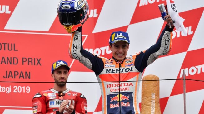 Pebalap Repsol Honda, Marc Marquez (kanan), merayakan kemenangan di balapan MotoGP Jepang di Sirkuit Motegi, Minggu (20/10/2019). Diikuti kemudian oleh Andrea Dovizioso (Ducati). [AFP/Toshifumi Kitamura]