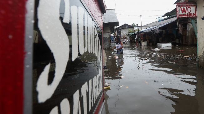 Warga melintasi jalan yang terendam banjir di kawasan Duren Tiga, Jakarta Selatan, Jumat (24/1). [Suara.com/Angga Budhiyanto]