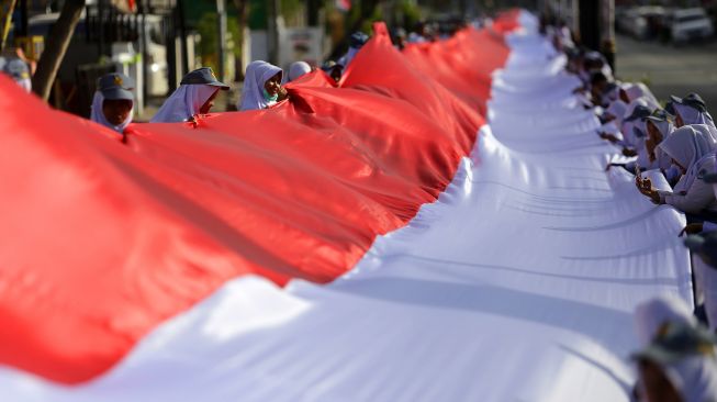 Sejumlah pelajar membentangkan kain merah putih di Kota Gorontalo, Gorontalo, Kamis (23/1). [ANTARA FOTO/Adiwinata Solihin]