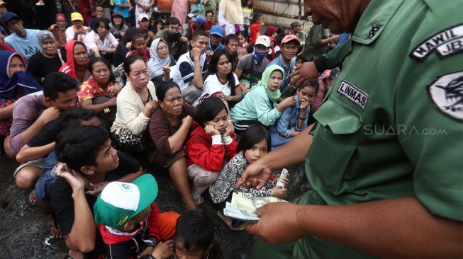 Petugas membagikan angpau kepada sejumlah warga dan pengemis musiman yang memadati Vihara Dharma Bhakti, Jakarta Barat, Sabtu (25/1). [Suara.com/Angga Budhiyanto]