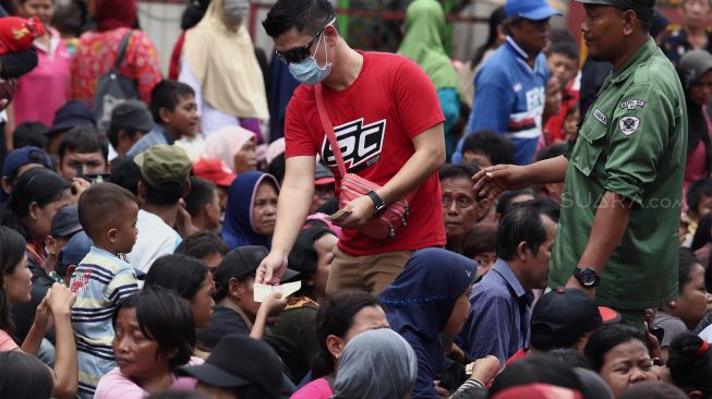 Sejumlah warga dan pengemis musiman menerima angpau di Vihara Dharma Bhakti, Jakarta Barat, Sabtu (25/1). [Suara.com/Angga Budhiyanto]