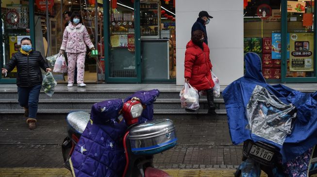 Orang-orang yang memakai masker wajah saat membeli makanan di pasar, Wuhan, China, Minggu (26/1/2020). [AFP/Hector Retamal].