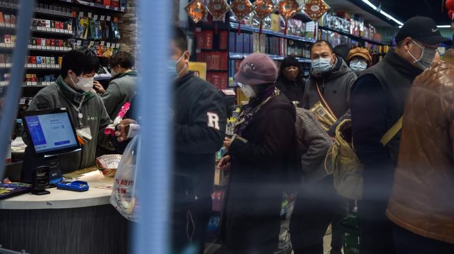 Orang-orang yang memakai masker wajah saat membeli makanan di pasar, Wuhan, Cina, Minggu (26/1). [Hector RETAMAL / AFP]