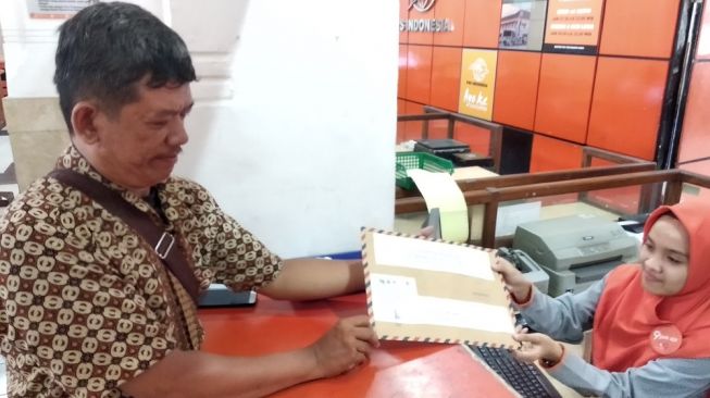 Ketua Indonesia Court Monitoring (ICM) Tri Wahyu mengirim tujuh surat aduan kepada tujuh guru bangsa untuk menegur Presiden Joko Widodo di Kantor Pos Besar Yogyakarta, Senin (27/1/2020). - (Suara.com/Baktora)