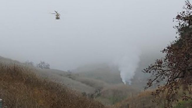 Helikopter jatuh dan mengeluarkan asap di Calabasas, California, Amerika Serikat, Minggu (26/1). [AFP Photo]
