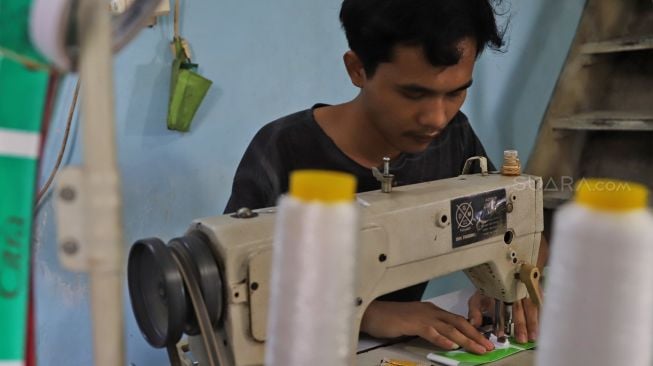 Pekerja menjahit sampah daur ulang yang nantinya akan diproses untuk menjadi kerajinan tangan di UKM rumah daur ulang milik Ibu Yanti, Pasar Minggu, Jakarta Selatan, Selasa (28/1). [Suara.com/ Alfian Winanto]