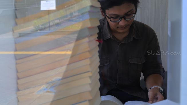 Pengunjung yang sedang membaca buku di Ruang Baca Jakarta di Stasiun BNI City, Jakarta Pusat, Rabu (29/01).[Suara.com/Alfian Winanto]
