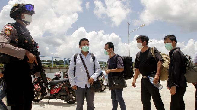 Seorang anggota polisi mengawal sejumlah warga negara China yang terdampar di perairan Rote Ndao setibanya di Lantamal VII Kupang, NTT, Kamis (30/1). [ANTARA FOTO/Kornelis Kaha]