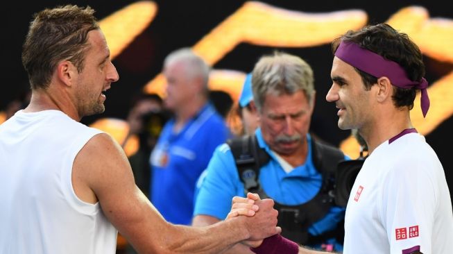 Petenis Swiss Roger Federer (kanan) bersalaman dengan lawannya Tennys Sandgren (AS) usai memenangi pertandingan perempat final tenis Australian Open di Melbourne, Selasa (28/1/2020). [AFP/William West]