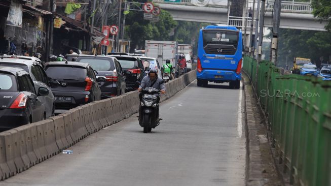 Pengendara sepeda motor berusaha menghindari razia Polisi lalu lintas di jalur khusus Transjakarta Sultan Agung, Manggarai, Jakarta, Jumat (31/1).  [Suara.com/Angga Budhiyanto]