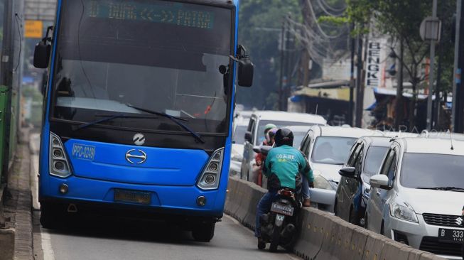 Pengendara sepeda motor berusaha menghindari razia Polisi lalu lintas di jalur khusus Transjakarta Sultan Agung, Manggarai, Jakarta, Jumat (31/1).  [Suara.com/Angga Budhiyanto]