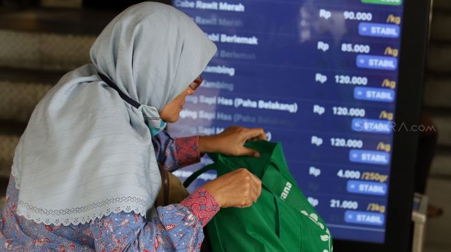 Pembeli membawa tas belanja saat berbelanja di Pasar Tebet Barat, Jakarta, Jumat (31/1). [Suara.com/Angga Budhiyanto]
