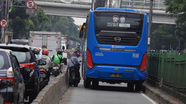 Pengendara sepeda motor berusaha menghindari razia Polisi lalu lintas di jalur khusus Transjakarta Sultan Agung, Manggarai, Jakarta, Jumat (31/1).  [Suara.com/Angga Budhiyanto]