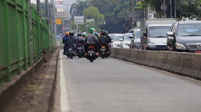 Pengendara sepeda motor berusaha menghindari razia Polisi lalu lintas di jalur khusus Transjakarta Sultan Agung, Manggarai, Jakarta, Jumat (31/1).  [Suara.com/Angga Budhiyanto]