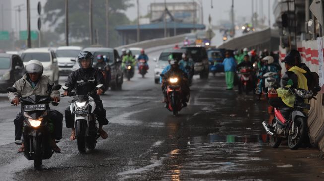 Pengendara motor yang mengenakan jas hujan saat melewati daerah Kuningan, Jakarta Selatan. Sebagai ilustrasi [Suara.com/Alfian Winanto].