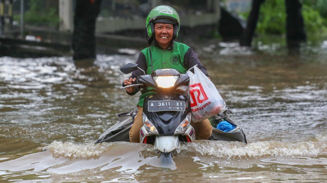 Pengendara melintasi banjir di Jalan Raya Regency, Kota Tangerang, Banten, Sabtu (1/2).  [ANTARA FOTO/Fauzan]
