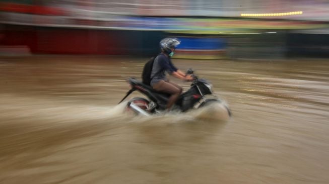 Pengendara melintasi banjir di Jalan Raya Regency, Kota Tangerang, Banten, Sabtu (1/2).  [ANTARA FOTO/Fauzan]
