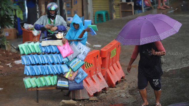 Penjual jas hujan yang sedang berjualan di pinggir jalan di daerah Kuningan, Jakarta Selatan, Sabtu (01/02).[Suara.com/Alfian Winanto]