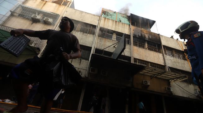 Petugas pemadam kebakaran berusaha memadamkan api yang membakar bangunan pertokoan di Pasar Tanah Abang Blok C, Jakarta, Senin (3/2). [Suara.com/Angga Budhiyanto]