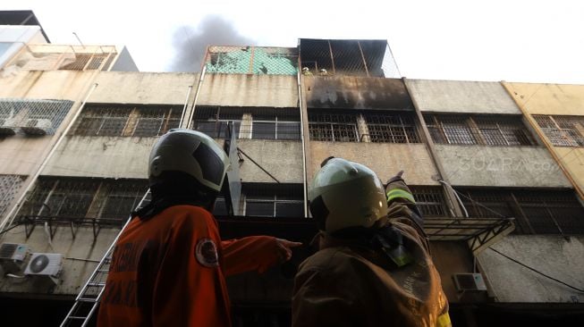 Petugas pemadam kebakaran berusaha memadamkan api yang membakar bangunan pertokoan di Pasar Tanah Abang Blok C, Jakarta, Senin (3/2). [Suara.com/Angga Budhiyanto]