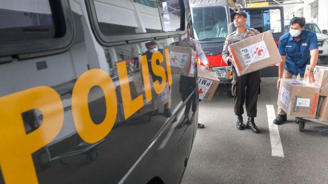 Personel Polisi mengangkat kardus yang berisi masker bantuan dari PMI pusat yang baru tiba di Bandara Raden Sadjad, Ranai, Natuna, Kepulauan Riau, Selasa (4/2).  [ANTARA FOTO/M Risyal Hidayat]