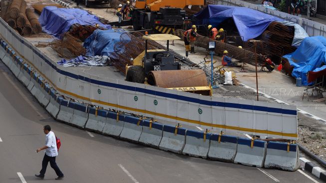 Seorang warga melintas di dekat proyek pembangunan underpass Senen Extension di Pasar Senen, Jakarta, Senin (3/2). [Suara.com/Angga Budhiyanto]