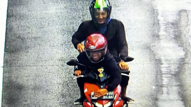 Seorang pengendara sepeda motor mencoba mengelabuhi polisi saat melintas di jalur busway dengan menutupi tanda nomor kendaraan (TNK) atau plat nomor kendaraan yang dikemudikan. (Foto dok. Ditlantas Polda Metro Jaya)