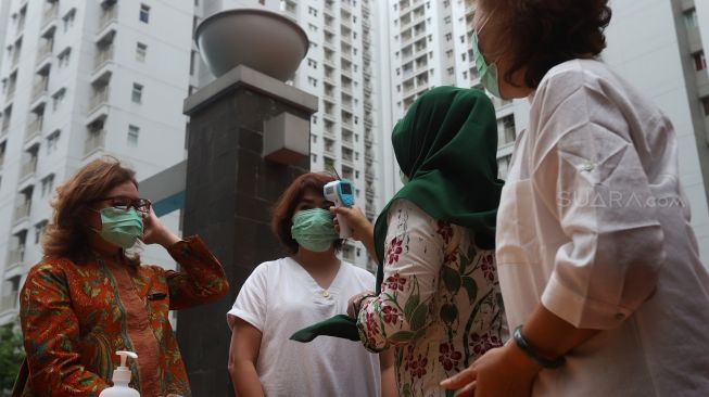warga di cek suhu tubuhnya saat sosialisasi mengenai Virus Corona di Tower Apartemen Mediterania Garden Residences 2, Jakarta Barat, Kamis (6/2).  [Suara.com/Angga Budhiyanto]