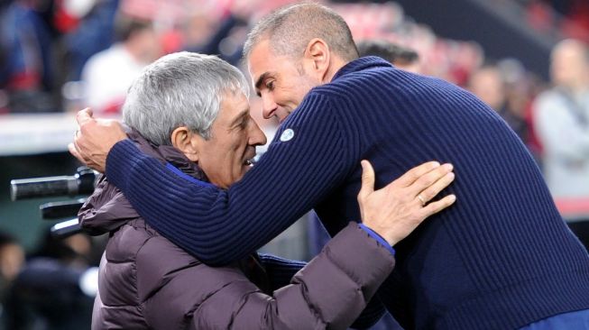 Pelatih Barcelona, Quique Setien (kiri) bercengkerama dengan pelatih Athletic Bilbao, Gaizka Garitano sebelum laga Copa del Rey 2019/2020 di Estadio San Mames, Bilbao, Jumat (7/2/2020) dini hari WIB. [ANDER GILLENEA / AFP]