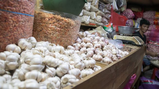 Pedagang bawang putih yang sedang menunggu pembeli di Pasar Induk Kramat jati, Jakarta Timur, Jumat (07/02). [Suara.com/Alfian Winanto]