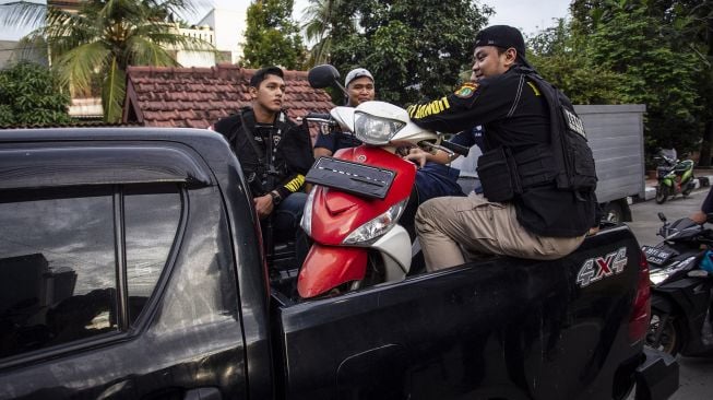 Petugas kepolisian membawa motor yang diduga digunakan tersangka saat rekonstruksi kasus penyiraman air keras terhadap penyidik KPK Novel Baswedan di kawasan Kelapa Gading, Jakarta, Jumat (7/2). [ANTARA FOTO/Dhemas Reviyanto]