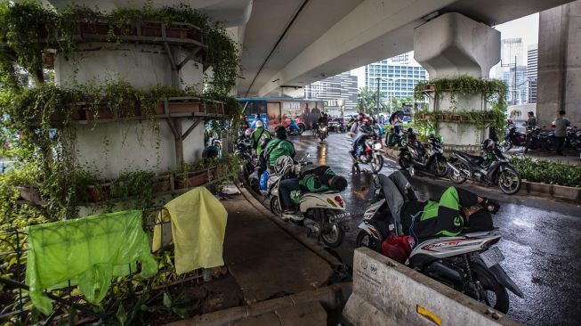 Para pengendara sepeda motor berteduh di bawah "flyover" Jalan KH Mas Mansyur saat hujan di Jakarta, Jumat (7/2). [ANTARA FOTO/Aprillio Akbar]