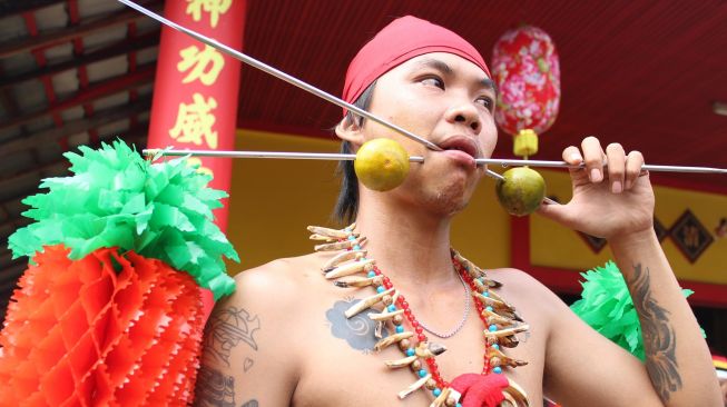 Seorang tatung (dukun Tionghoa yang kerasukan arwah leluhur) menusukan pipiny dengan besi tajam saat beratraksi di acara perayaan Cap Go Meh di Sungai Raya, Kabupaten Kubu Raya, Kalimantan Barat, Sabtu (8/2). [ANTARA FOTO/Jessica Helena Wuysang]