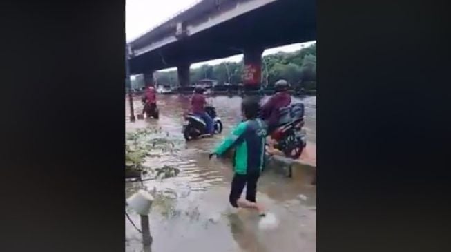 Driver ojol terperosok ke dalam lubang saat banjir (FB/yunirusmini)