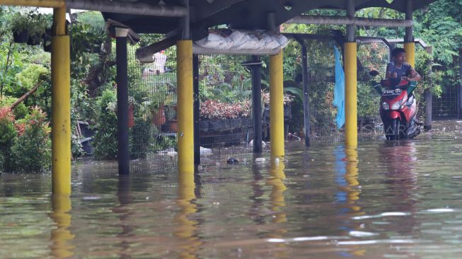 Warga duduk diatas motornya yang terjebak banjir di Jalan Cempaka Putih, Jakarta Pusat, Sabtu (08/02).[Suara.com/Alfian Winanto]
