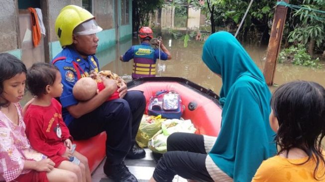 Petugas Pemadam Kebakaran Jakarta Timur mengevakuasi balita dan anak-anak yang terjebak banjir di kawasan Kramat Jati, Sabtu (9/2/2020). Banjir di kawasan itu terjadi akibat hujan dengan intensitas tinggi yang berlangsung sejak malam hari. [Damkar Jaktim]