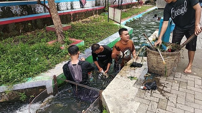 Beberapa warga membersihkan sampah yang berada di aliran irigasi di Kampung Mrican, Kelurahan Giwangan, Kecamatan Umbulharjo, Kota Yogyakarta, Minggu (9/2/2020). - (Suara.com/Baktora)