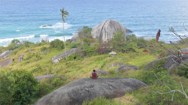 Seorang wisatawan duduk di atas gugusan batu granit di Geopark Tanjung Senubing, Ranai, Natuna, Kepulauan Riau, Minggu (9/2). [ANTARA FOTO/M Risyal Hidayat]