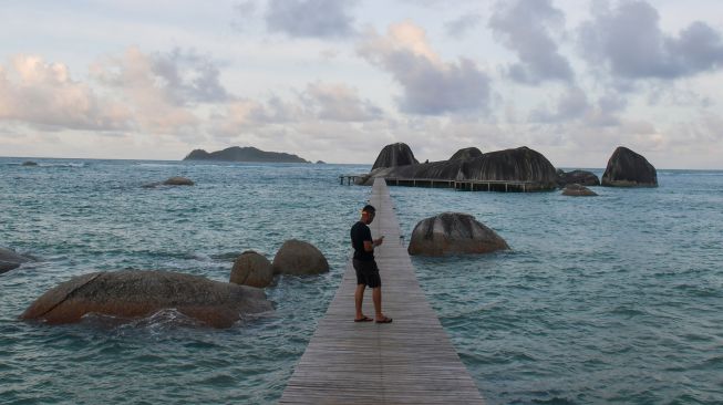 Seorang wisatawan berdiri di atas jembatan di antara gugusan batu granit di kawasan Sepempang, Natuna, Kepulauan Riau, Minggu (9/2). [ANTARA FOTO/M Risyal Hidayat]