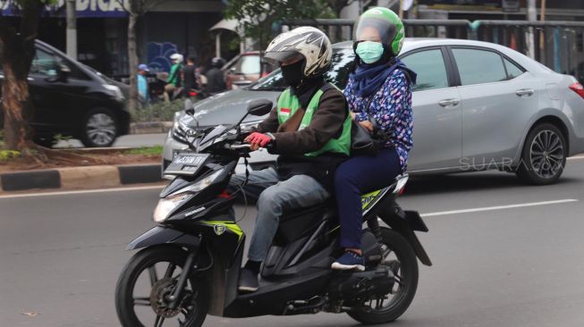 Pengendara motor yang menggunakan masker saat melintasi daerah Pasar Pramuka, Jakarta, Selasa, (11/2).[Suara.com/Alfian Winanto]
