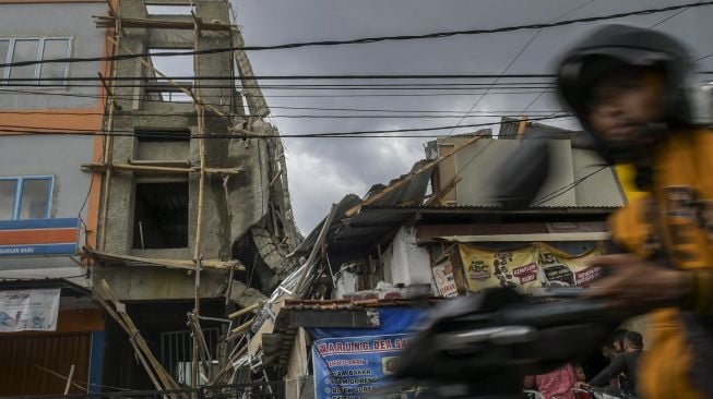 Pengendara motor melintas di samping bangunan yang ambruk di Jalan Pisangan Baru, Matraman, Jakarta, Selasa (11/2). [ANTARA FOTO/Galih Pradipta]
