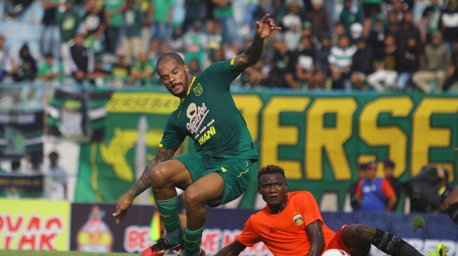 Pesepak bola Persebaya David Aparecido da Silva (kiri) mencoba melewati hadangan pesepak bola Bhayangkara FC Ni Bibola Guy (kanan) saat pertandingan penyisihan grup A Piala Gubernur Jawa Timur di Stadion Gelora Bangkalan (SGB), Bangkalan, Jawa Timur, Rabu (12/2/2020). Persebaya kalah lawan Bhayangkara FC dengan skor akhir 0-1. ANTARA FOTO/Moch Asim/ama.