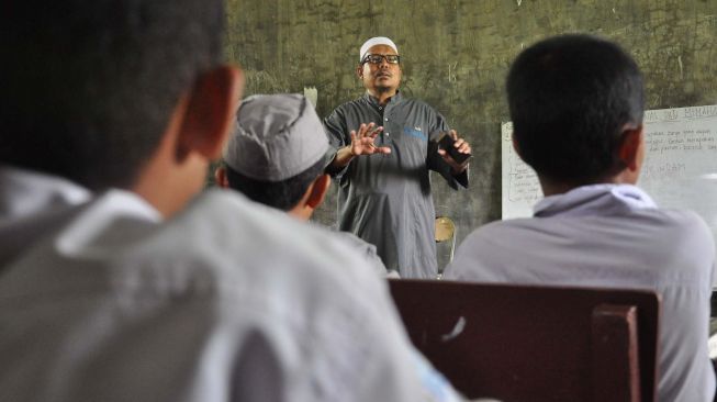 Pendiri Pondok Pesantren Al Hidayah yang merupakan mantan terpidana kasus terorisme Khairul Ghazali (tengah) menyampaikan materi pelajaran kepada santri yang merupakan anak mantan teroris, di Deli Serdang, Sumatera Utara, Rabu (12/2). [ANTARA FOTO/Septianda Perdana]
