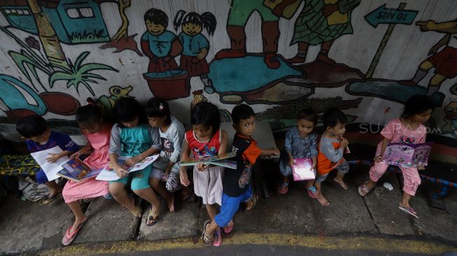 Anak-anak membaca buku di Taman Bacaan di kawasan Jembatan Lima, Jakarta,  Kamis (13/2). [Suara.com/Angga Budhiyanto]