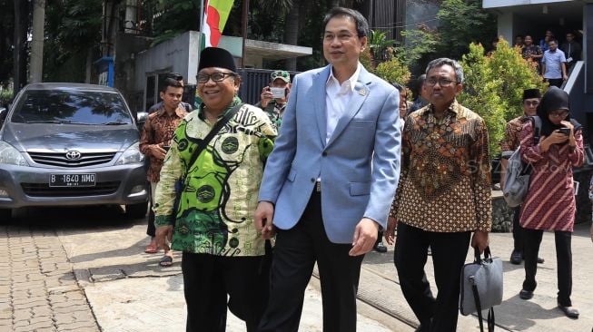 Wakil Ketua DPR Koordinator Bidang Politik, Hukum dan Keamanan, Azis Syamsuddin (kanan) dan Ketua Umum Lembaga Dakwah Islam Indonesia (LDII), Abdullah Syam (kiri) berjalan untuk mencoba Bus listrik yang digagas LDII, Rabu (12/02). [Suara.com/Oke Atmaja]