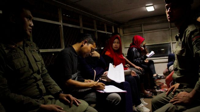 Anggota Satuan Polisi Pamong Praja (Satpol PP) mendata penhuni kamar yang terjaring razia di salah satu wisma di Makassar, Sulawesi Selatan, Kamis (13/2) malam.  [ANTARA FOTO/Arnas Padda]