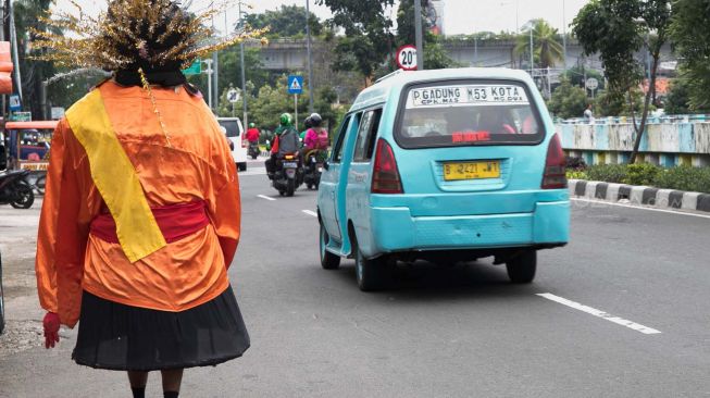 Pengamen ondel-ondel berjalan di Kemayoran, Jakarta Pusat, Kamis (13/02). [Suara.com/Alfian Winanto]

