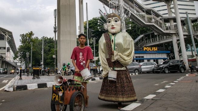 Pengamen ondel-ondel melintas di Kebayora Lama, Jakarta Selatan, Kamis (13/02). [Suara.com/Alfian Winanto]