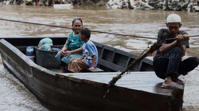 Warga menaiki perahu eretan untuk menyeberangi Kali Ciliwung di kawasan Manggarai, Jakarta, Jumat (14/2). [Suara.com/Angga Budhiyanto]