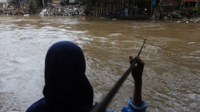 Seorang warga menunggu perahu eretan untuk menyeberangi Kali Ciliwung di kawasan Manggarai, Jakarta, Jumat (14/2). [Suara.com/Angga Budhiyanto]